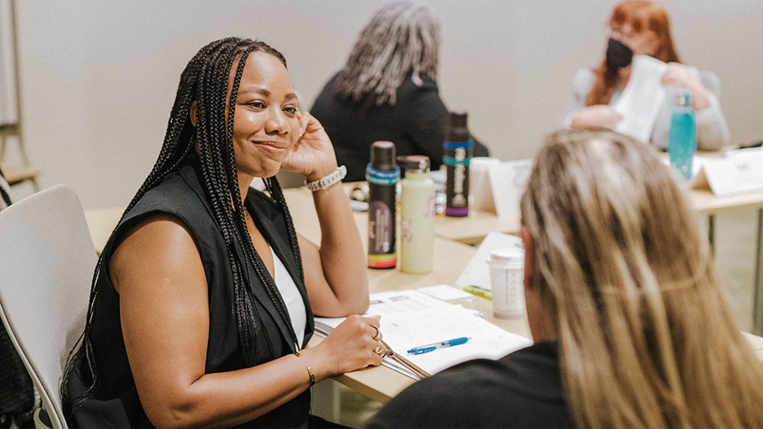 A woman smiles at someone sitting next to her with two other people in the background