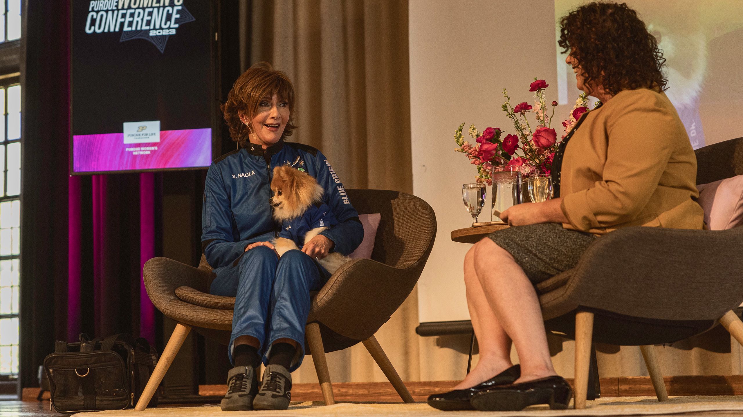 Two women chatting while sitting in chairs on a stage