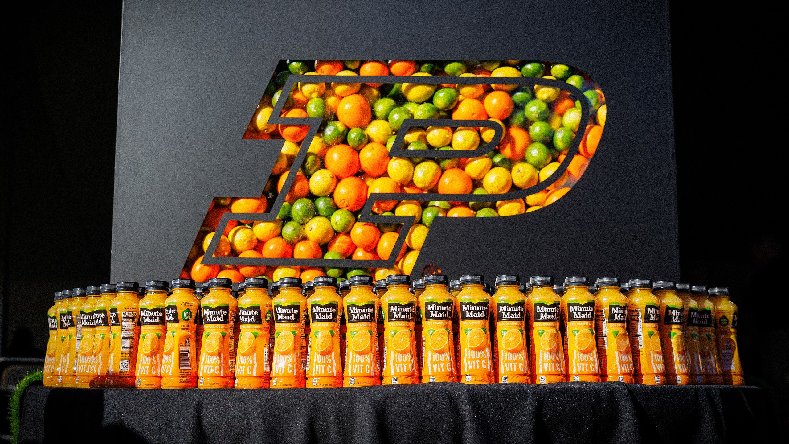 A display of orange juice bottles and lemons, limes, and oranges