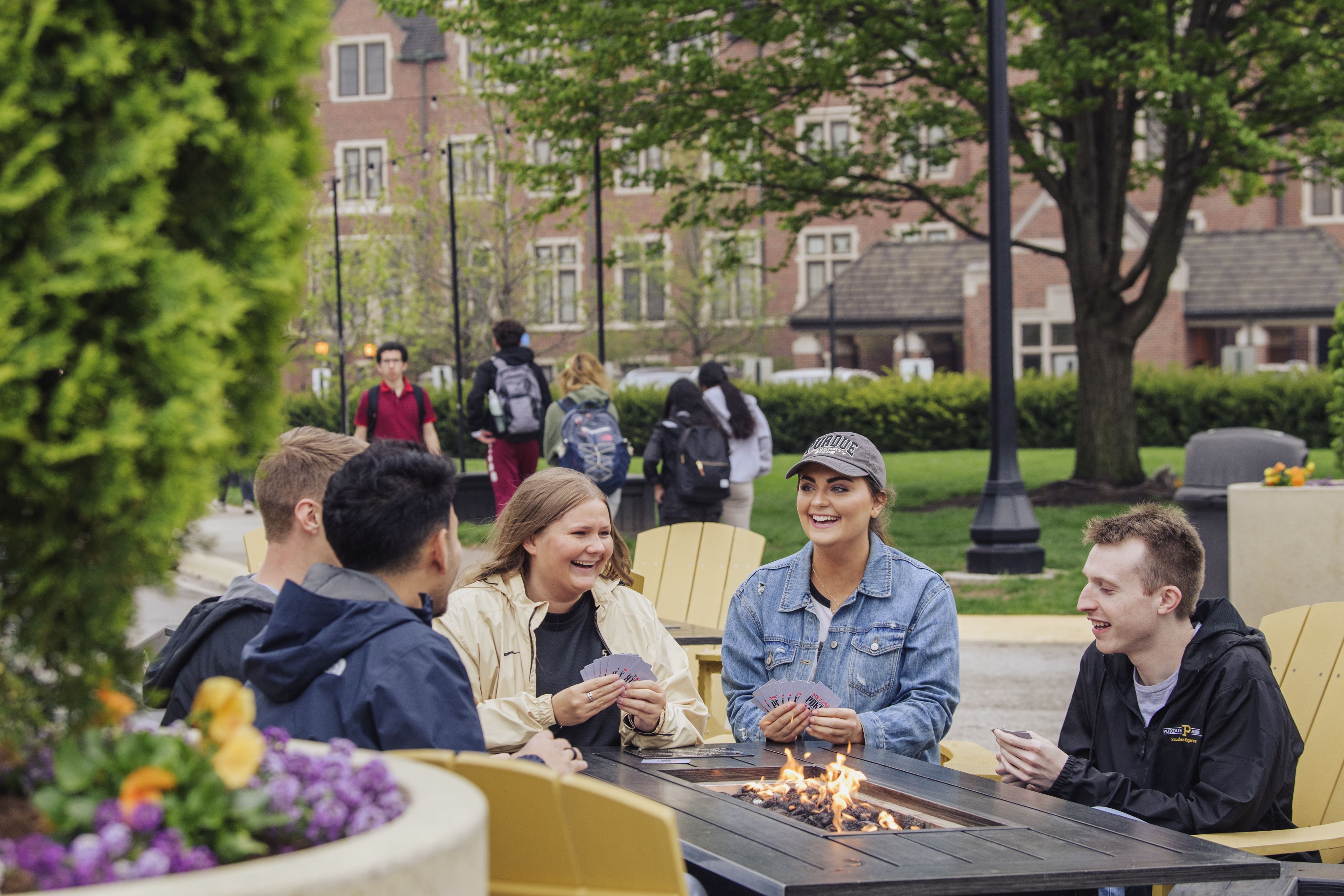 Purdue students sit around a fire pit while playing cards