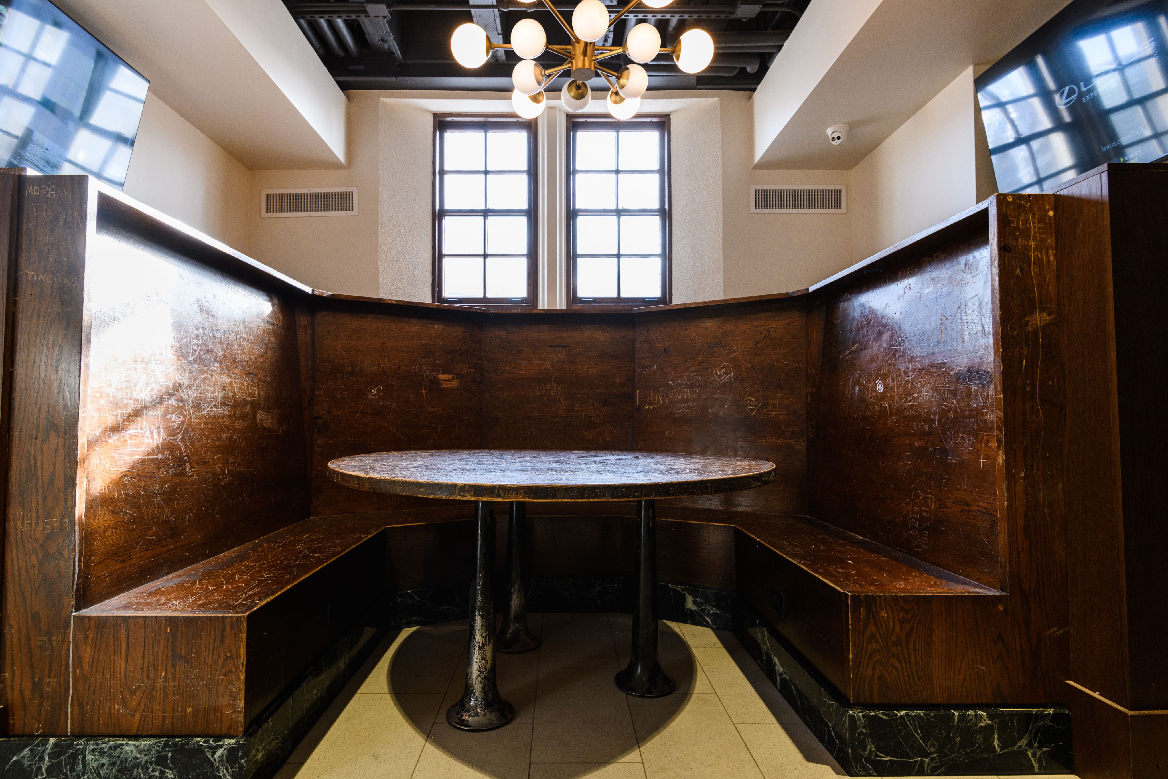 Wooden U-shaped booth with hundreds of signatures etched and painted on the surface
