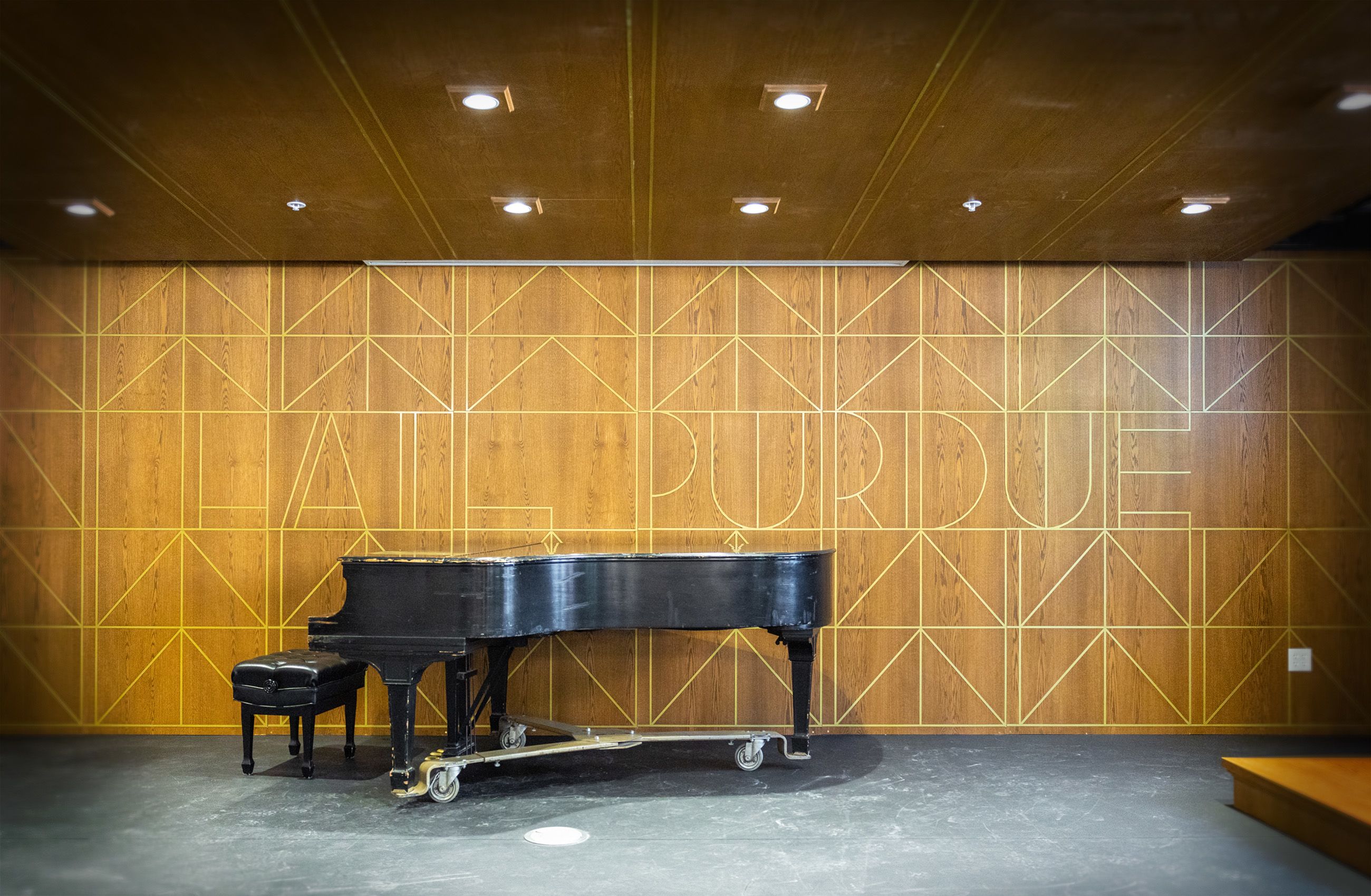 Stage with a black piano and the words "Hail Purdue" on the wall