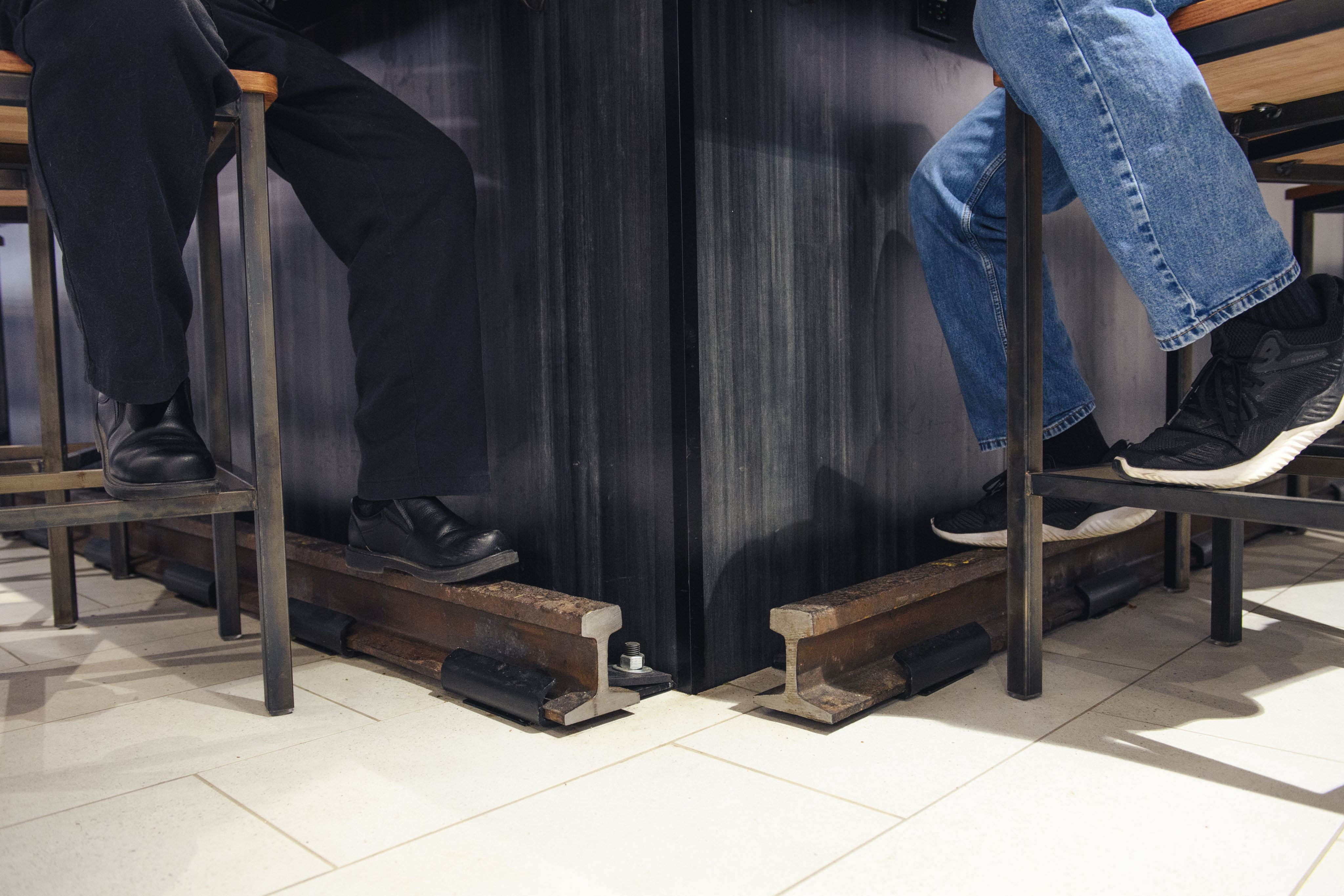 Two people sit at the corner of the bar, resting their feet on the metal rails