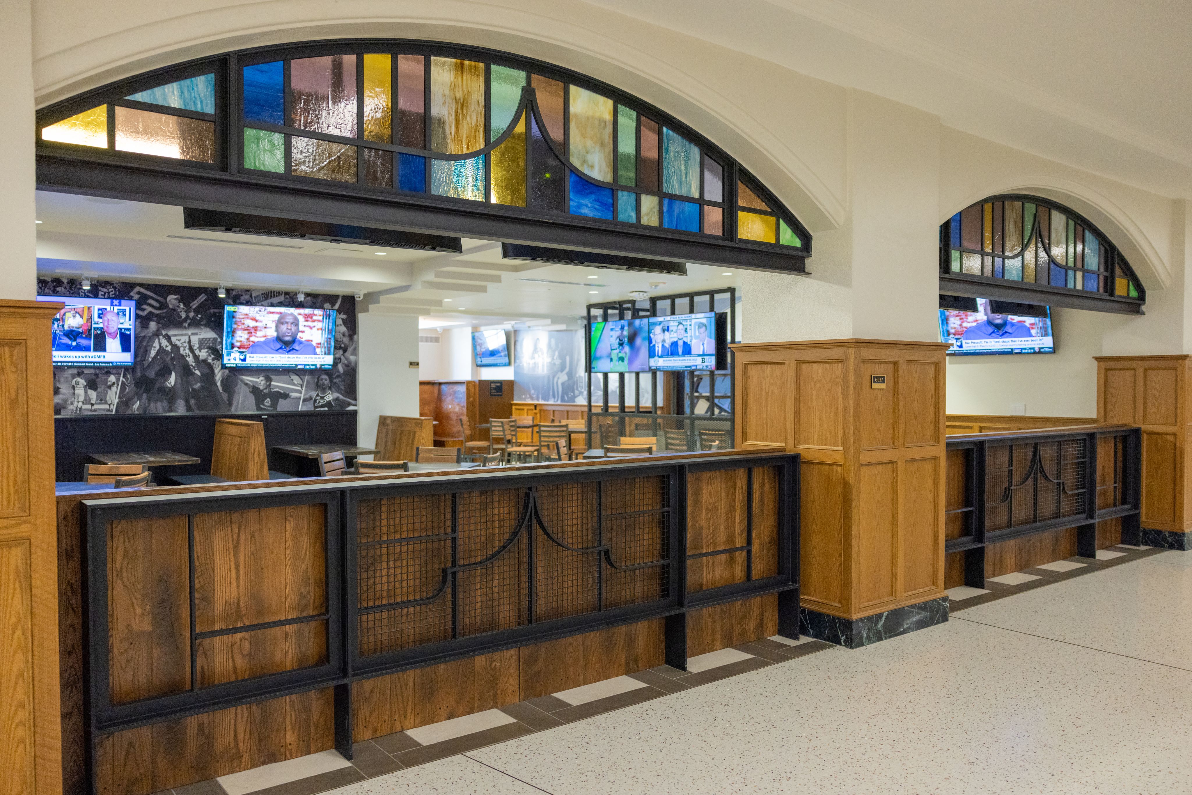 Stained glass windows and iron rails accent the wall the divides the dining area from the hallway