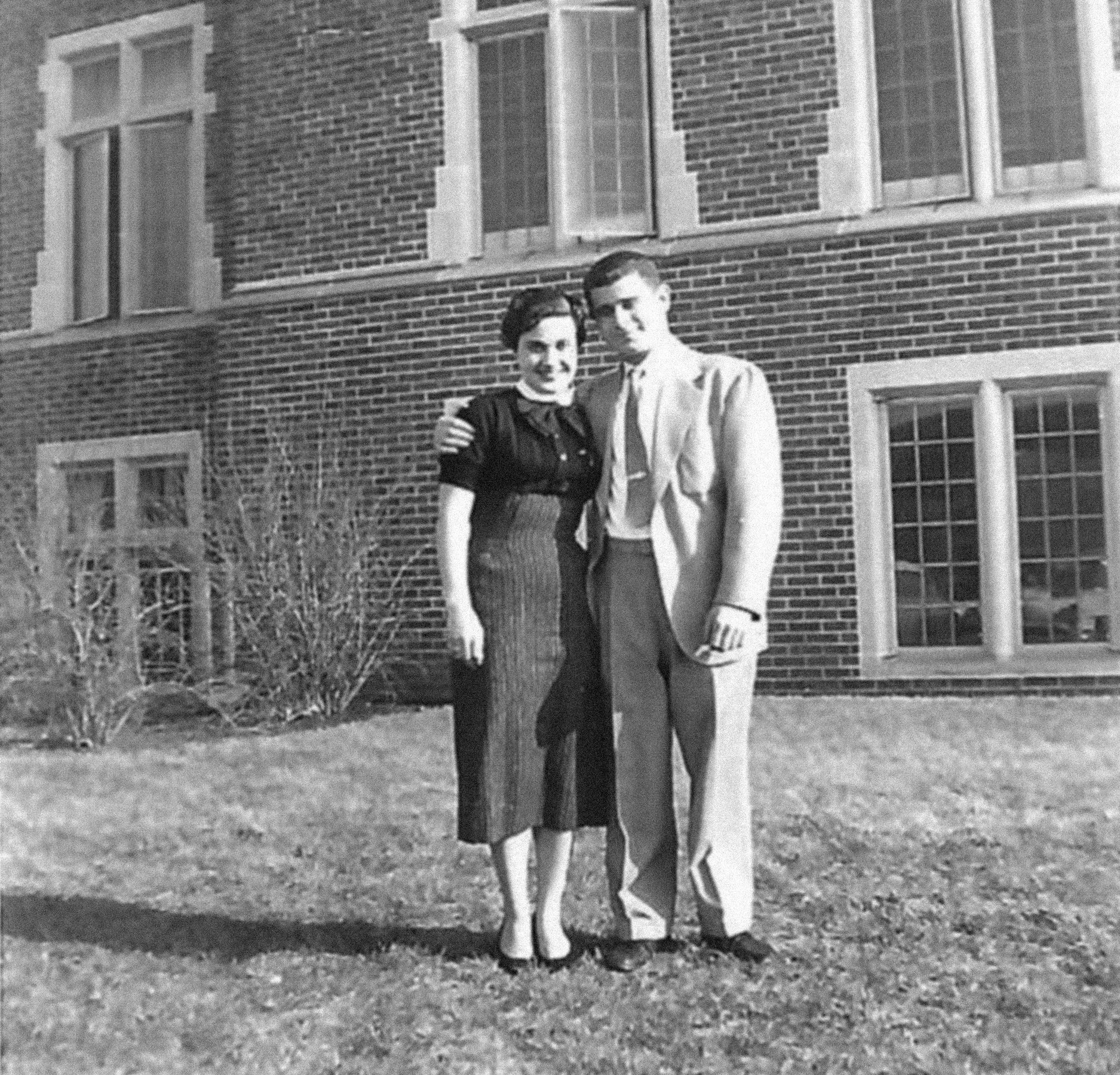 A black and white photo of young man and woman standing together