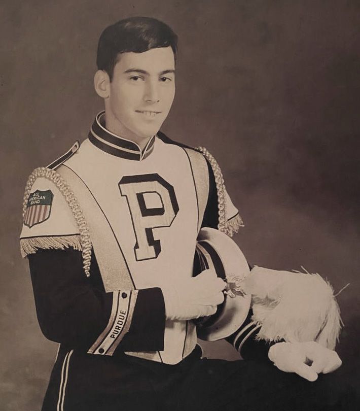The image shows young Marc Hagle in a Purdue Marching Band uniform