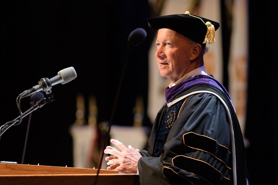 The image shows President Mitch Daniels at commencement podium