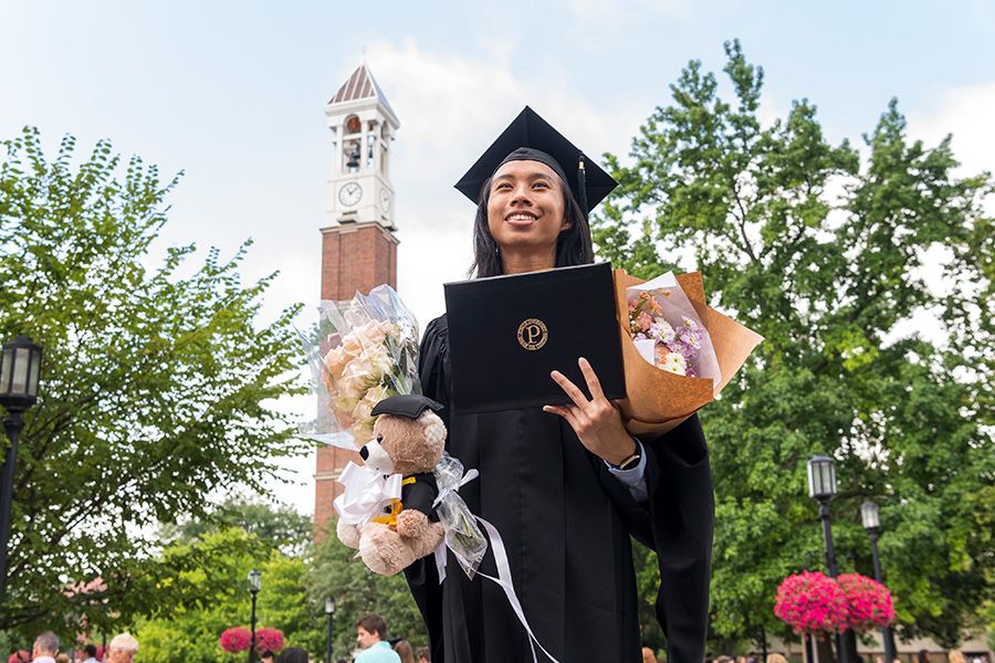 The image shows a Purdue student at commencement