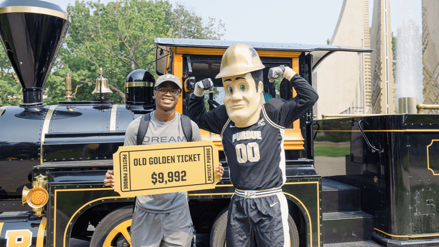 Male student stands beside mascot Purdue Pete in front of the Boilermaker Special