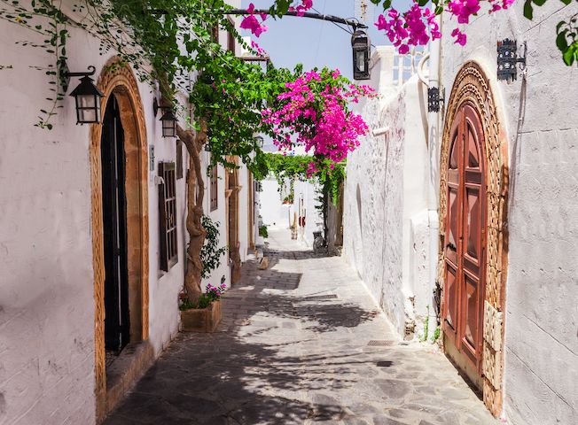 View down an alleyway with hanging flowers and greenery in Rhodes, Greece