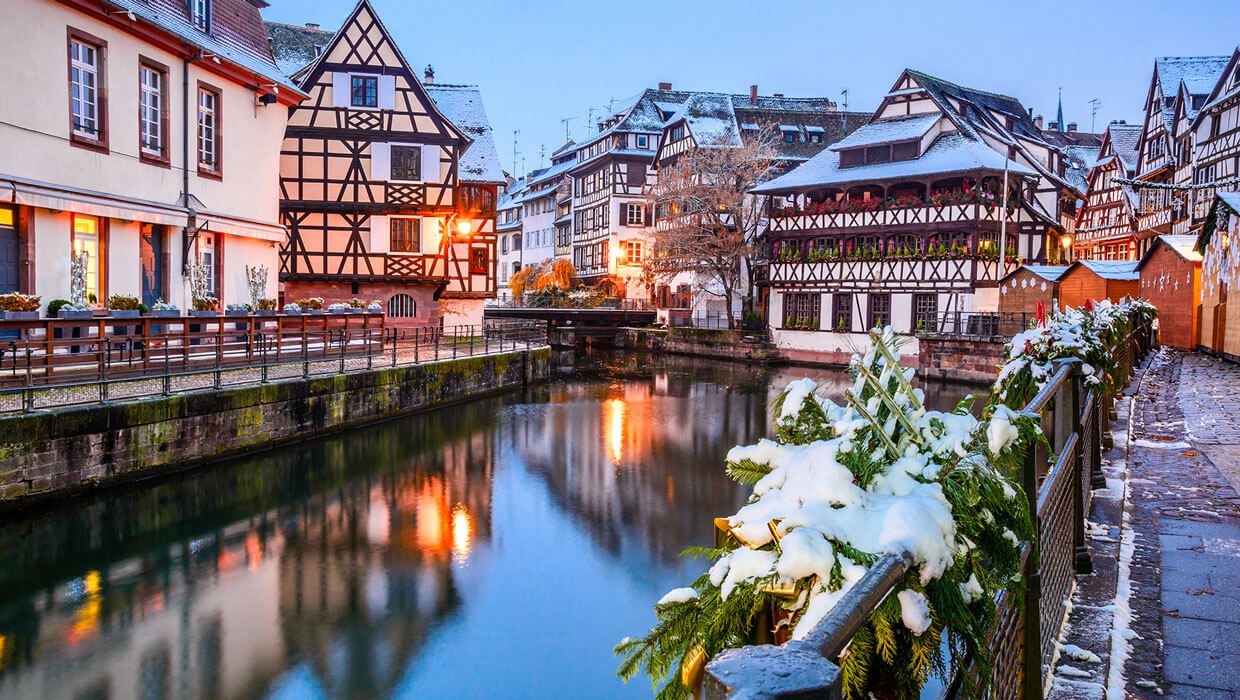 View of the river during the evening with snow on the surrounding buildings and bushes in Strasbourg